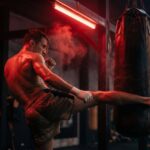Combattant de boxe thaï qui travaille son cardio en frappant un sac dans une salle sombre